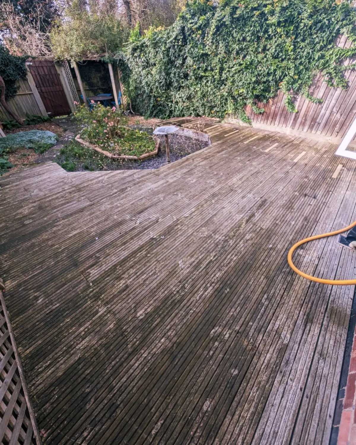 Timber decking in South Ribble before cleaning, with grey weathering and algae