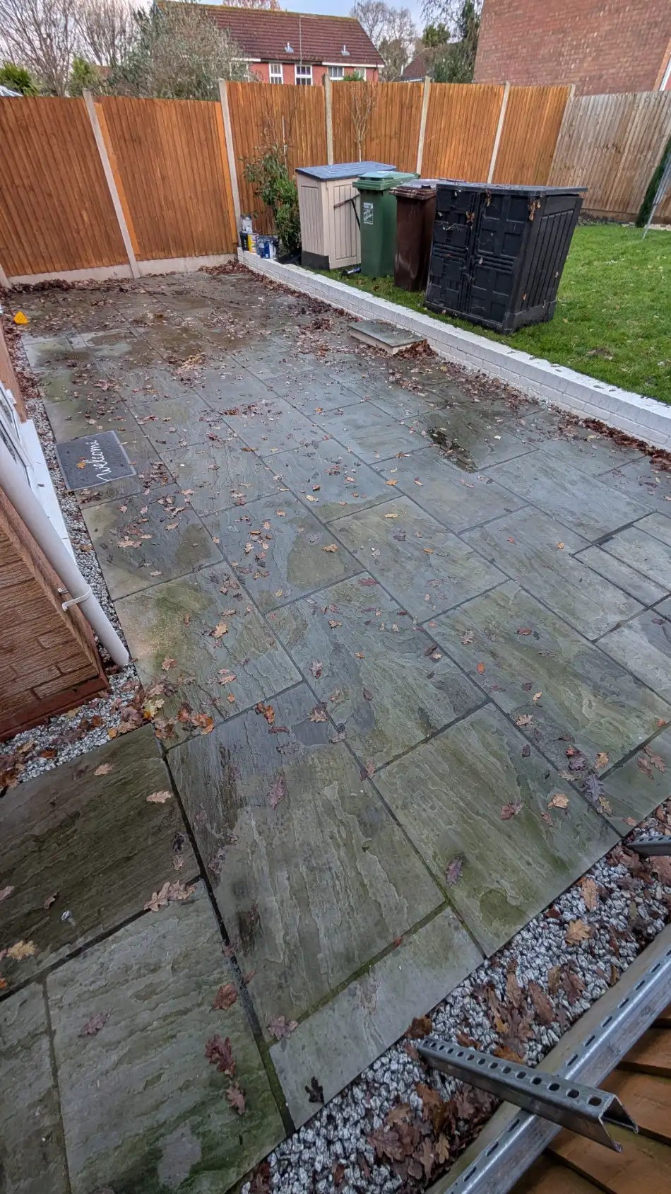 Patio paving slabs before cleaning, covered in wet leaves and standing water
