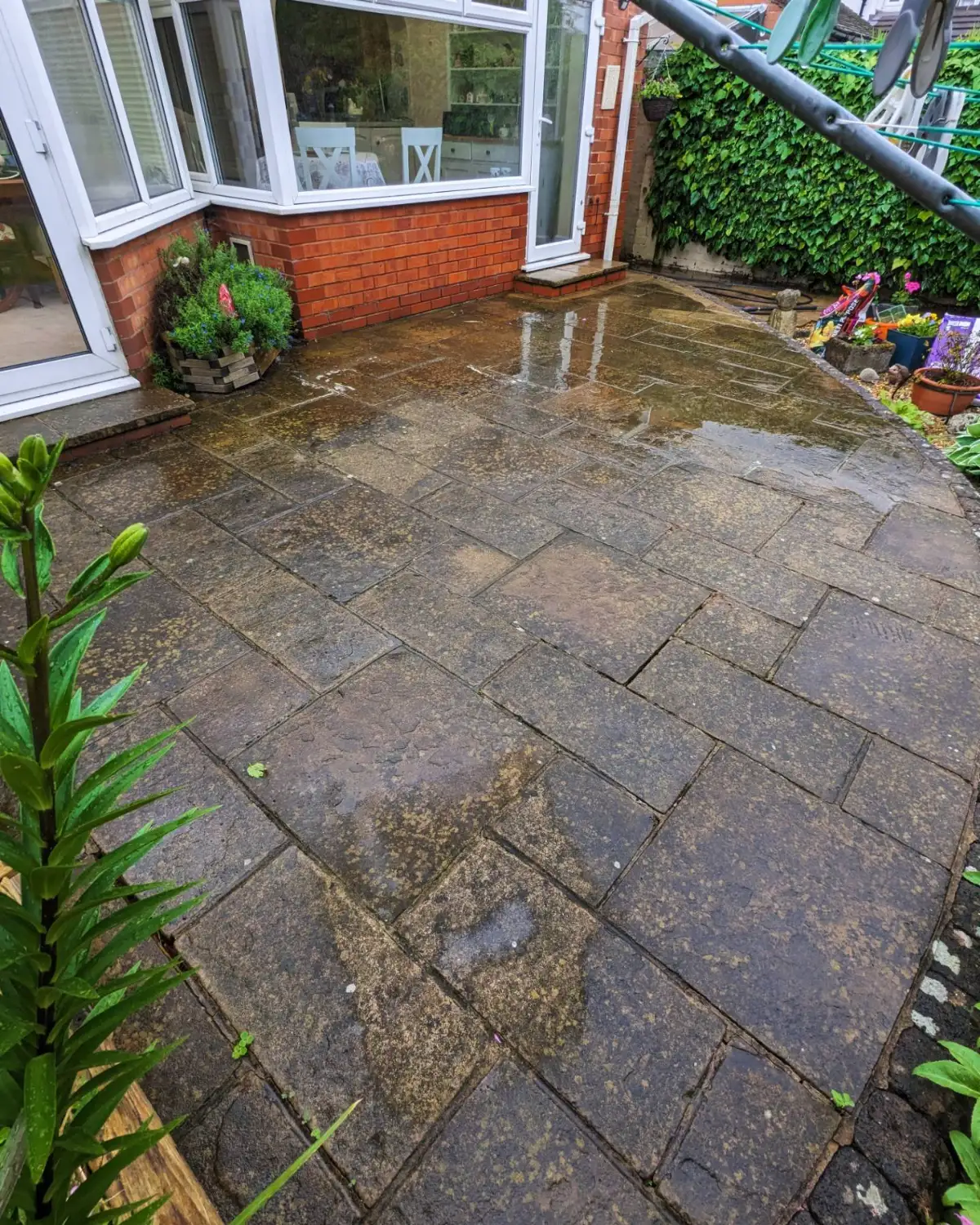 Patio in Much Hoole before cleaning, with wet staining across the flags